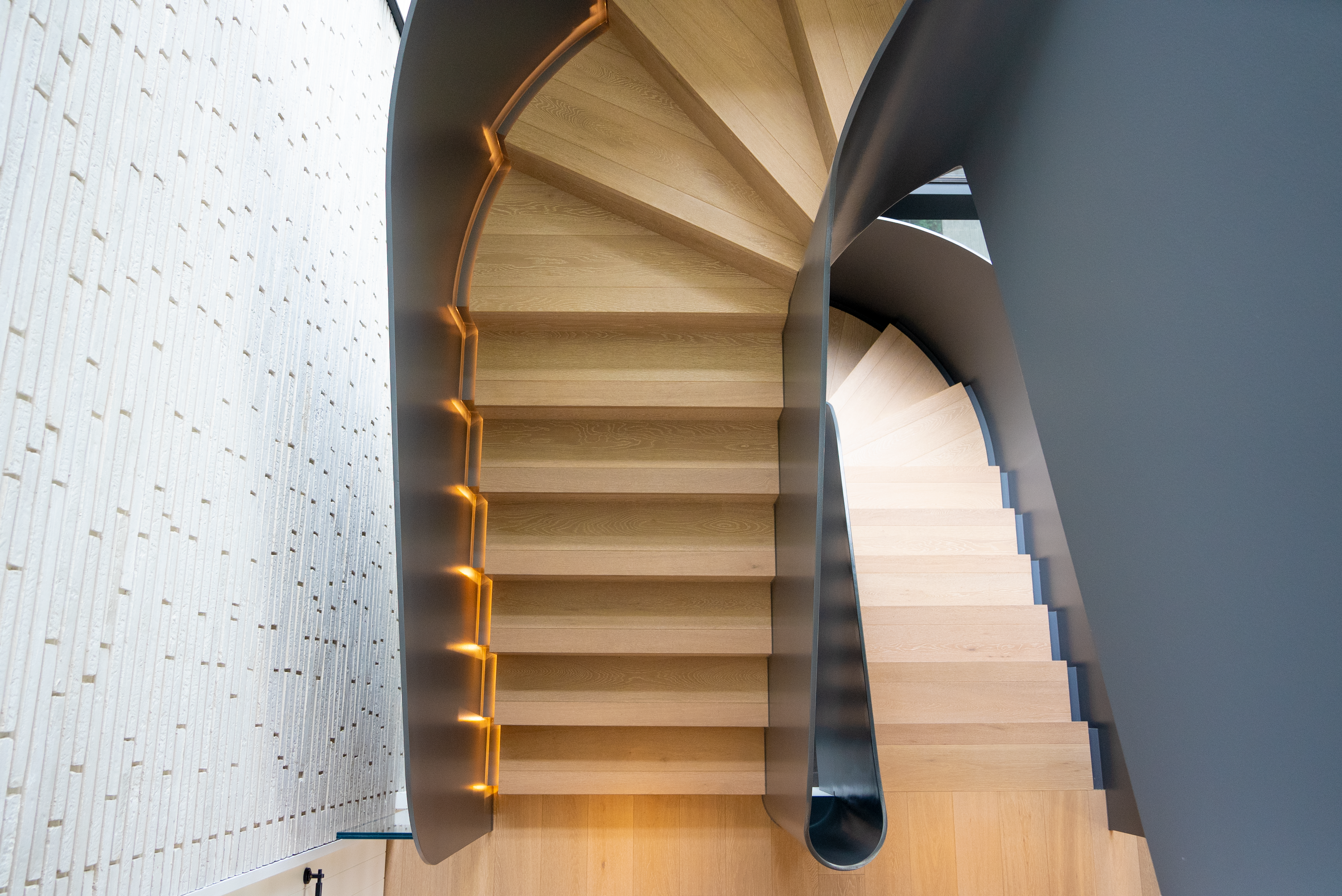 Dawn House &mdash; curvaceous steel staircase with integrated LED scribed into each timber tread